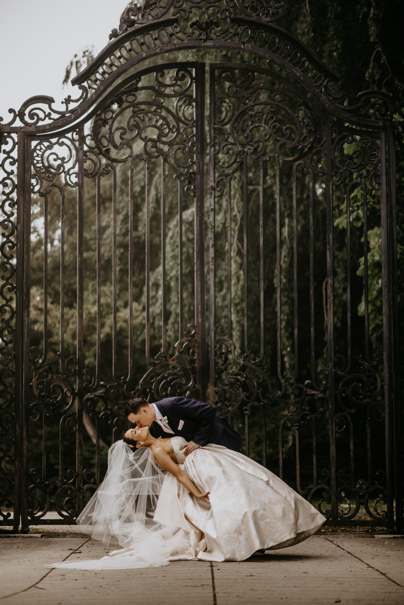 Artistic black and white wedding portrait behind an ornate iron gate